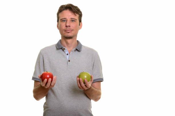 istock Handsome man holding red and green apple 668624024