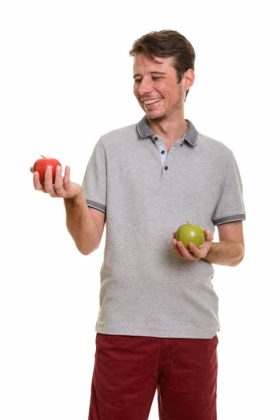 istock Happy handsome man standing while looking at red apple and holding green apple 668624124