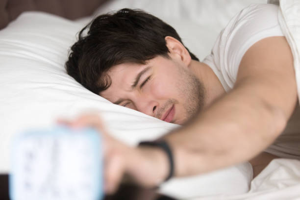 istock Sleepy man turning off alarm clock, time to wake up 668624300