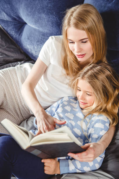 istock Mother and daughter reading book 668630144