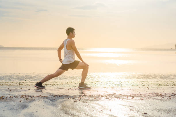 istock Young asian man doing yoga exercise at sunset beach 668630832