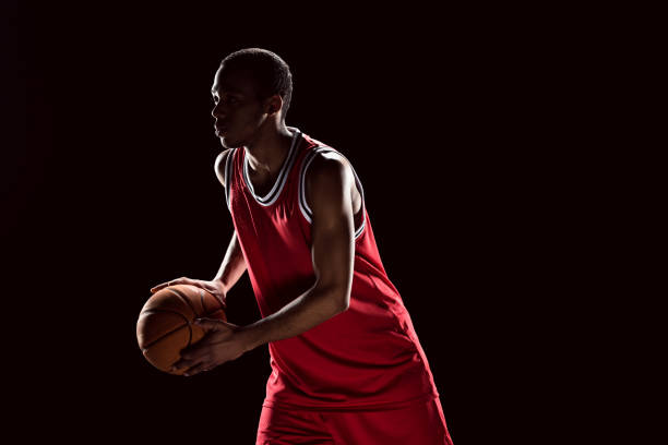 istock Handsome african american man playing basketball on black 668634458