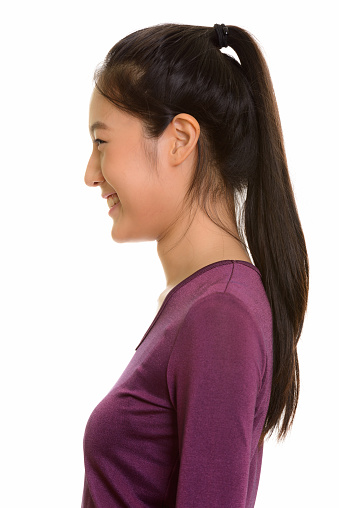 Profile view of face of young happy Asian teenage girl smiling vertical shot