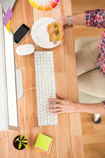 istock Casual designer working with computer and eating sandwich 668637446