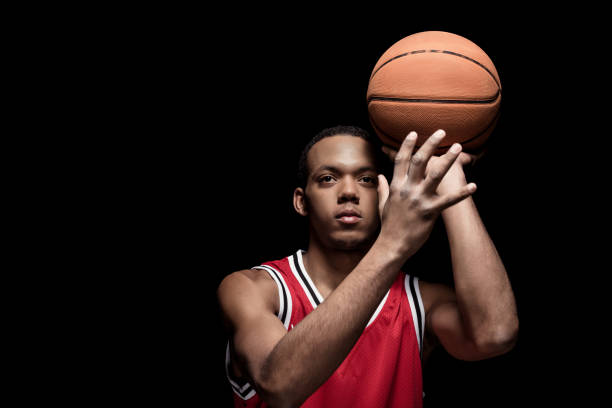 istock Young athletic man in uniform playing basketball with ball on black 668638536
