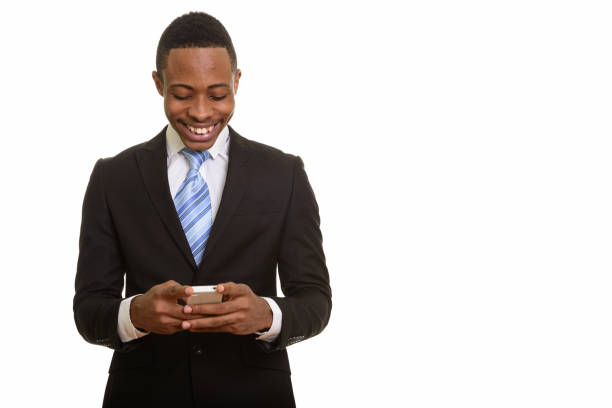 Young happy African businessman smiling and using mobile phone horizontal shot