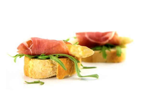 Canape with asparagus, ham and rocket salad isolated on a white background, closeup, selective focus, narrow depth of fieldCanapes with asparagus, ham and rocket salad on a bright background, closeup, selective focus, narrow depth of field