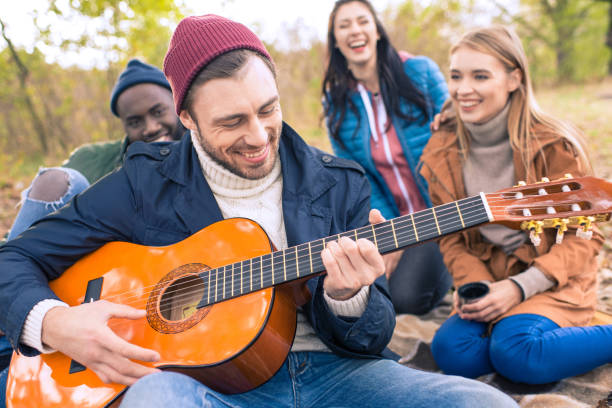 istock Friends enjoying guitar in autumn park 668670432