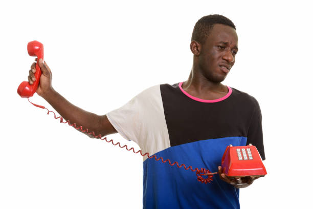 istock Young African man looking annoyed while holding old telephone 668684128