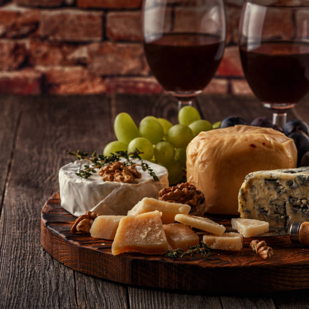 istock Cheese, nuts, grapes and red wine on wooden background 668684368