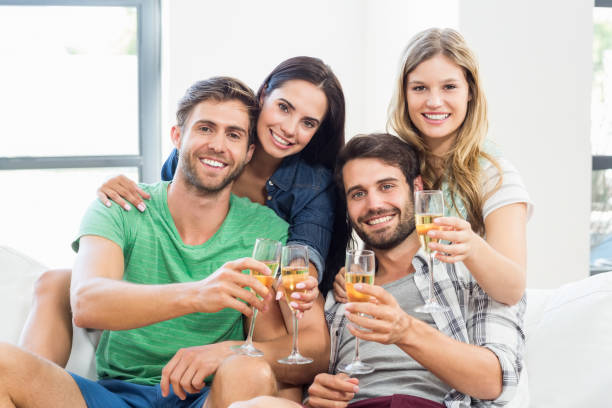 istock Smiling friends sitting on sofa drinking alcohol 668684562