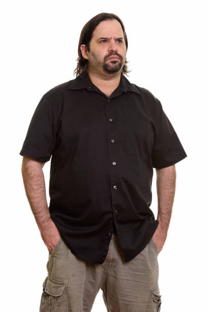 istock overweight bearded man standing while thinking with hands in pockets 668697650