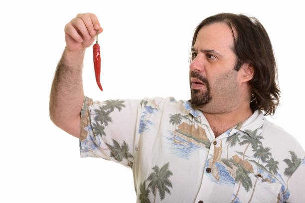 Close up of overweight bearded tourist man looking at spicy red chili pepper
