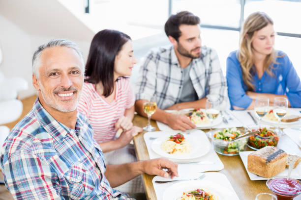 istock Man sitting with friends at dinning table 668704362