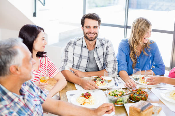 istock Man sitting with friends at dinning table 668704496