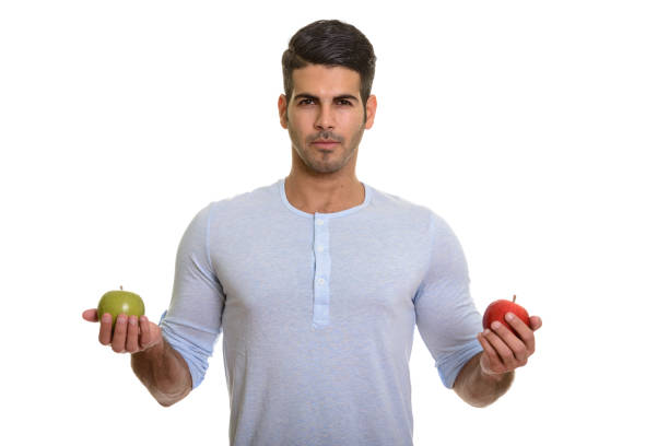 istock Young handsome Persian man holding red apple and green apple 668705248