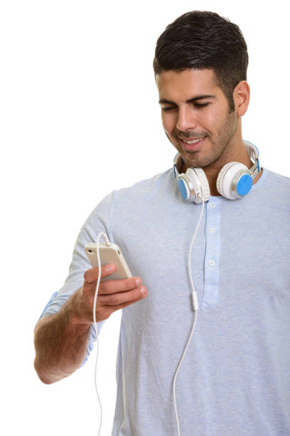 istock Young happy Persian man smiling and using mobile phone while wearing headphones around neck 668705416