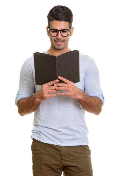 istock Young happy Persian man smiling and standing while reading book with eyeglasses 668707814