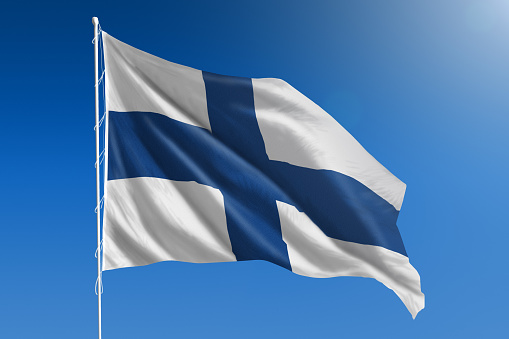The National flag of Finland blowing in the wind in front of a clear blue sky