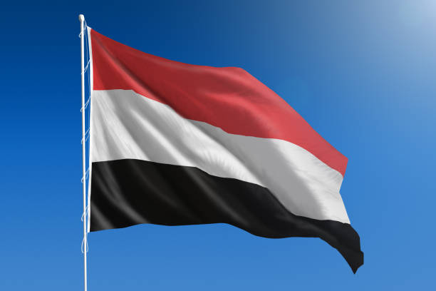 National flag of Yemen on clear blue sky stock photo