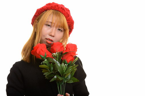 Close up of young Asian woman holding red roses while looking sad horizontal shot