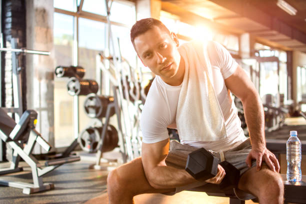 istock Young handsome man exercising with a dumbbell in the gym. 668717708