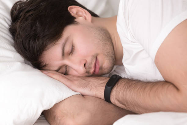 istock Man asleep in bed wearing smart wristband for sleep tracking 668717744