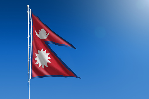 The National flag of Nepal blowing in the wind in front of a clear blue sky