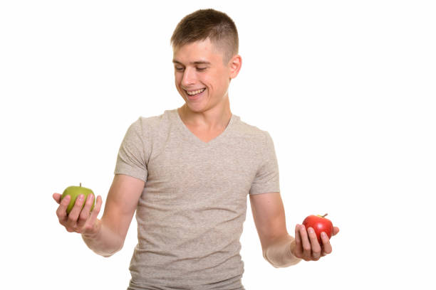 istock Young happy handsome man smiling while choosing between red apple and green apple 668720964