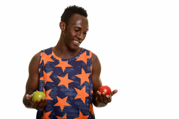 istock Young happy black African man smiling and choosing between green apple and red apple 668743716