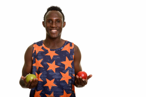 istock Young happy black African man smiling while holding green apple and red apple 668743744
