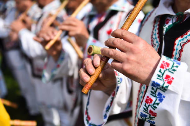 People in romanian traditional costumes singing at wooden flutes