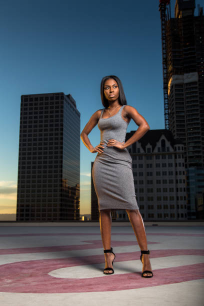 istock Sophisticated Woman Posing with Hands on Hips on rooftop 668745598