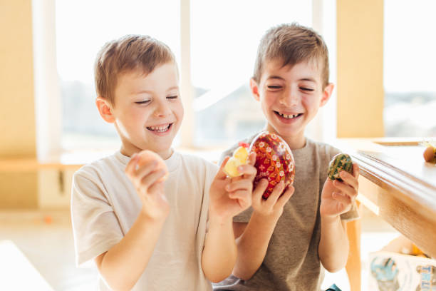 deux garçons retenant des oeufs de pâques et sourient l'un à l'autre - face paint child animal little boys photos et images de collection