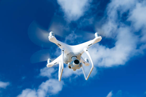drone flying over sea. white drone hovering in a bright blue sky stock photo