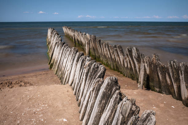 Old fishing boat pier wooden poles near Koshrags. Baltic sea can be seen in the background