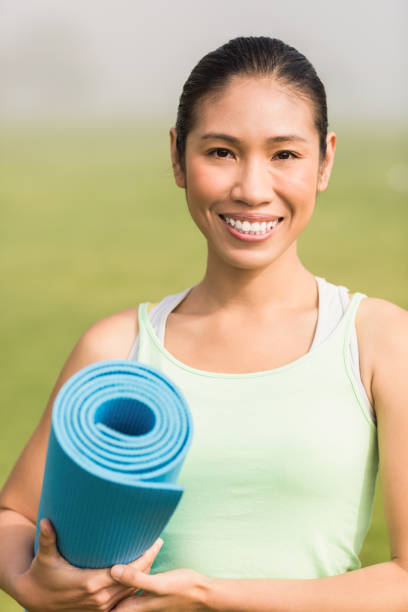 istock Smiling sporty woman holding exercise mat 668782796