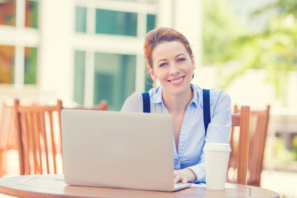 istock young smiling woman working on laptop outside corporate office drinking coffee 668832096