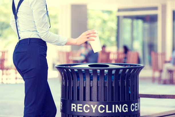 istock cropped image woman's hand throwing empty paper coffee cup in recycling bin 668832328