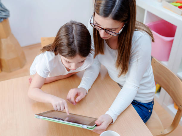 istock Woman with child playing and learning with digital tablet indoors 668832584
