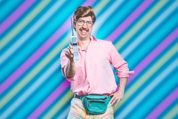 Nineties Tech and Fashion Style Man A man wearing fluorescent colored clothing and a fanny pack holds up a 1980's - 1990's cellular brick phone, representing state of the art style and technology for that time.  Colorful early 90's styled background. vintage people stock pictures, royalty-free photos & images