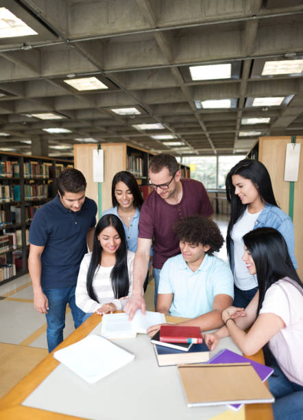 istock Librarian helping a group of students studying at the library 668843352
