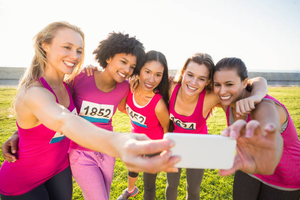 istock Runners supporting breast cancer marathon and taking selfies 668852464