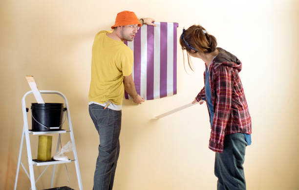 Friends applying wallpaper to wall