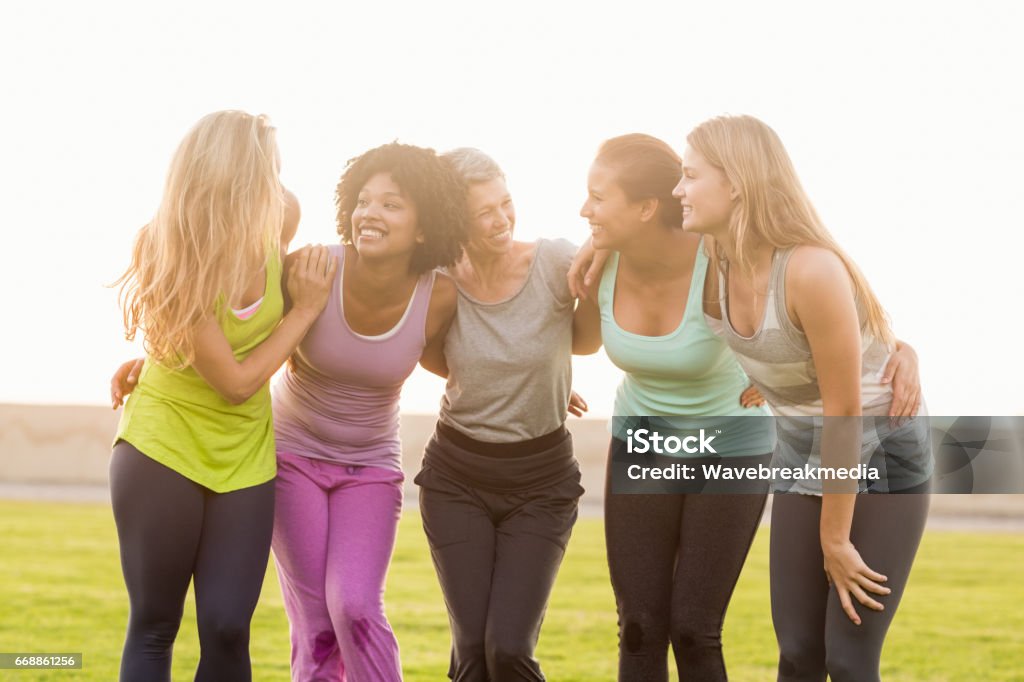 Smiling sporty women with arms around each other Smiling sporty women with arms around each other in parkland Women Stock Photo