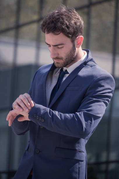 istock one young man, suit tie, looking at watch 668871140