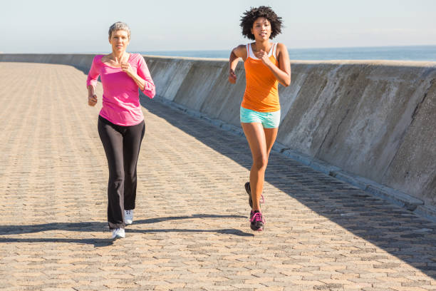 istock Two sporty women jogging together 668877222