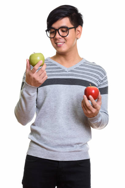 istock Happy Asian man smiling while choosing between red apple and green apple 668888104