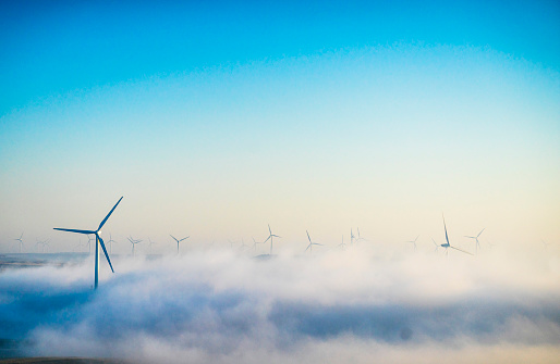 An electricity generating windmills on the wheat field against a dramatic cloudy sky in England