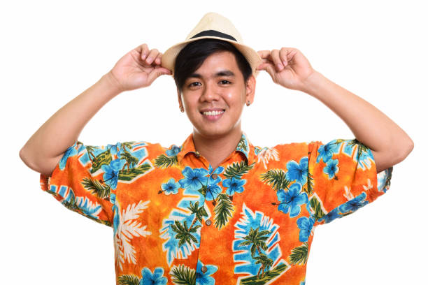 istock Young happy Asian tourist man smiling while holding hat with both hands 668888756